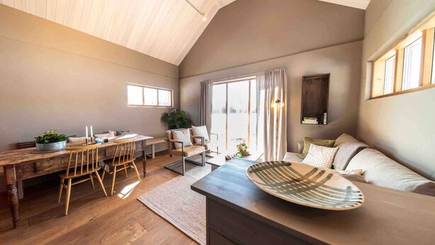 A spacious living area with a wooden dining table, a sofa, and a large decorative bowl.