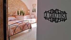 Ein Schlafzimmer mit einem Bett, einer Steinwand und einem dekorativen Schild mit der Aufschrift 'LA GRAZIOSA'.