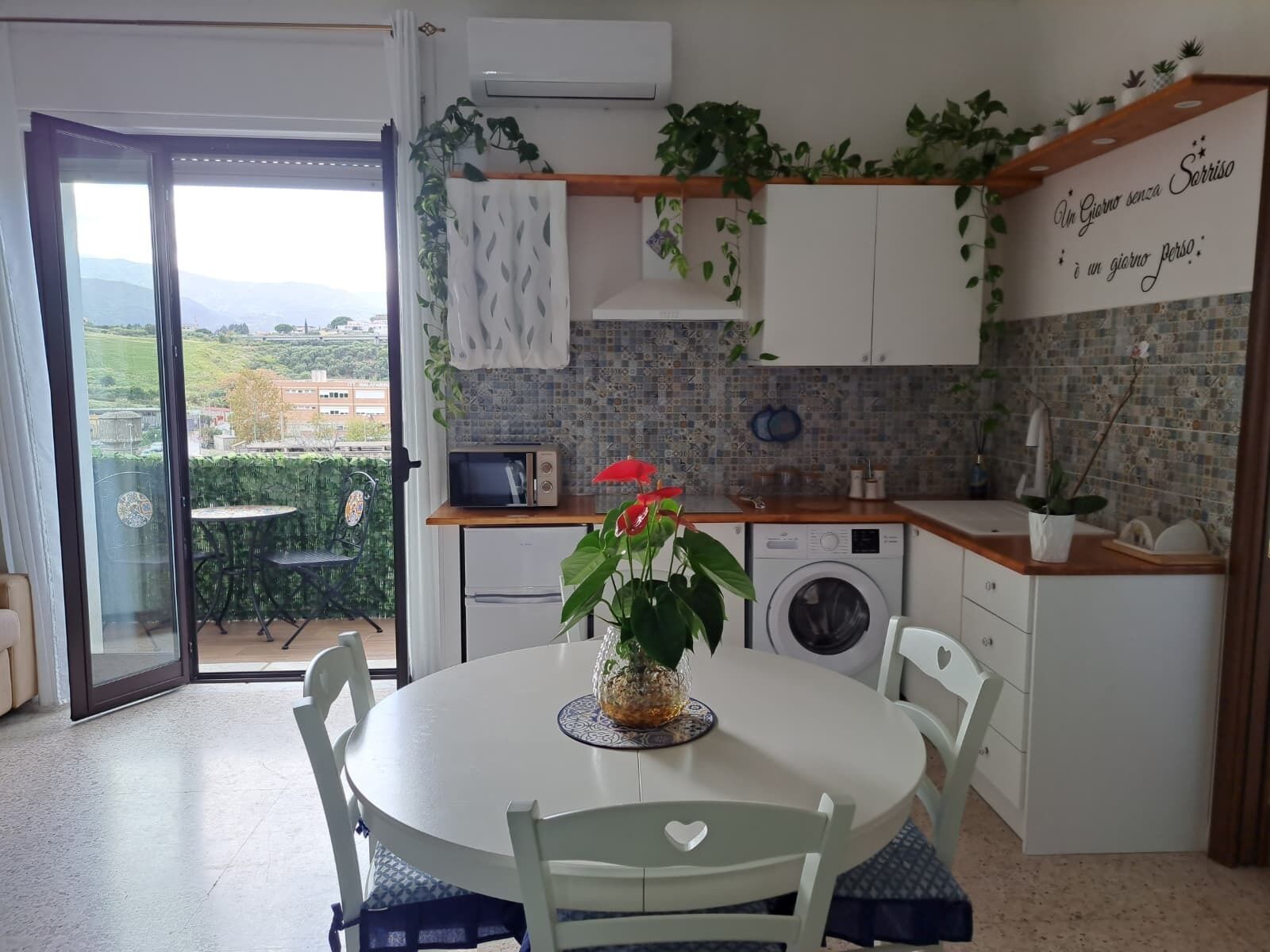 Cocina compacta con comedor, lavadora y vistas al exterior.