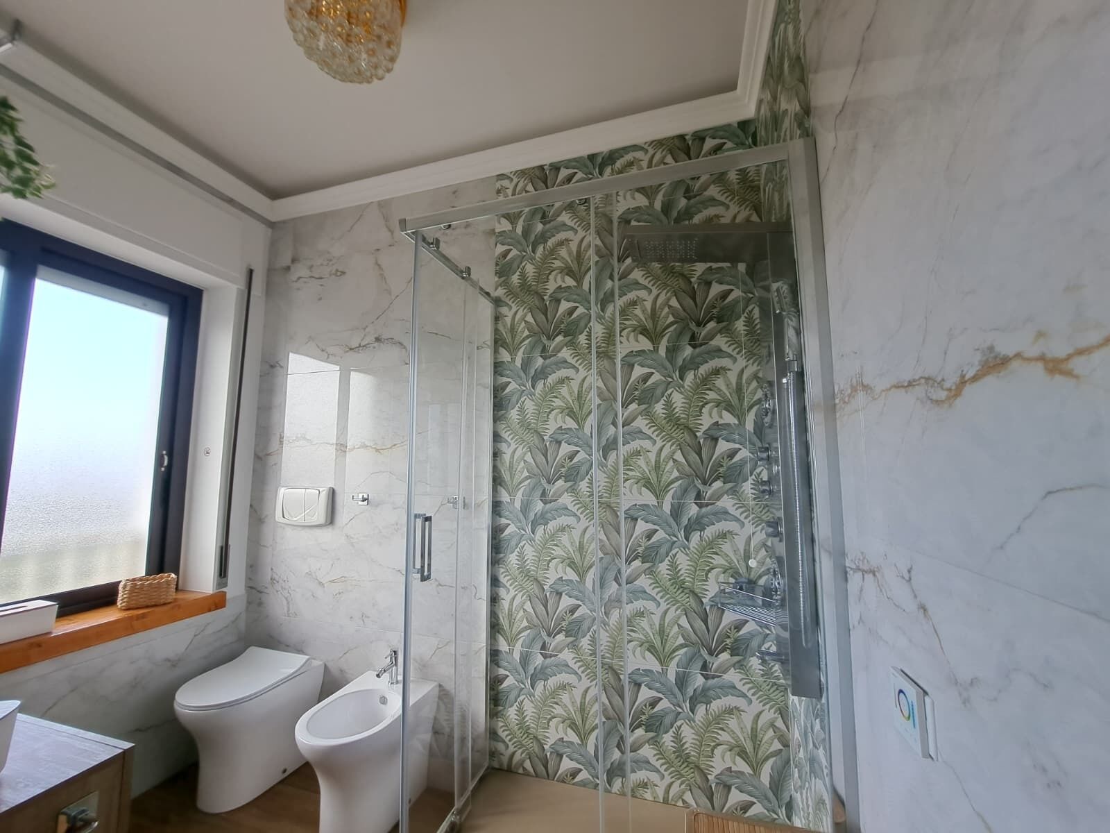 A bathroom with a glass shower enclosure, a toilet, and a bidet.
