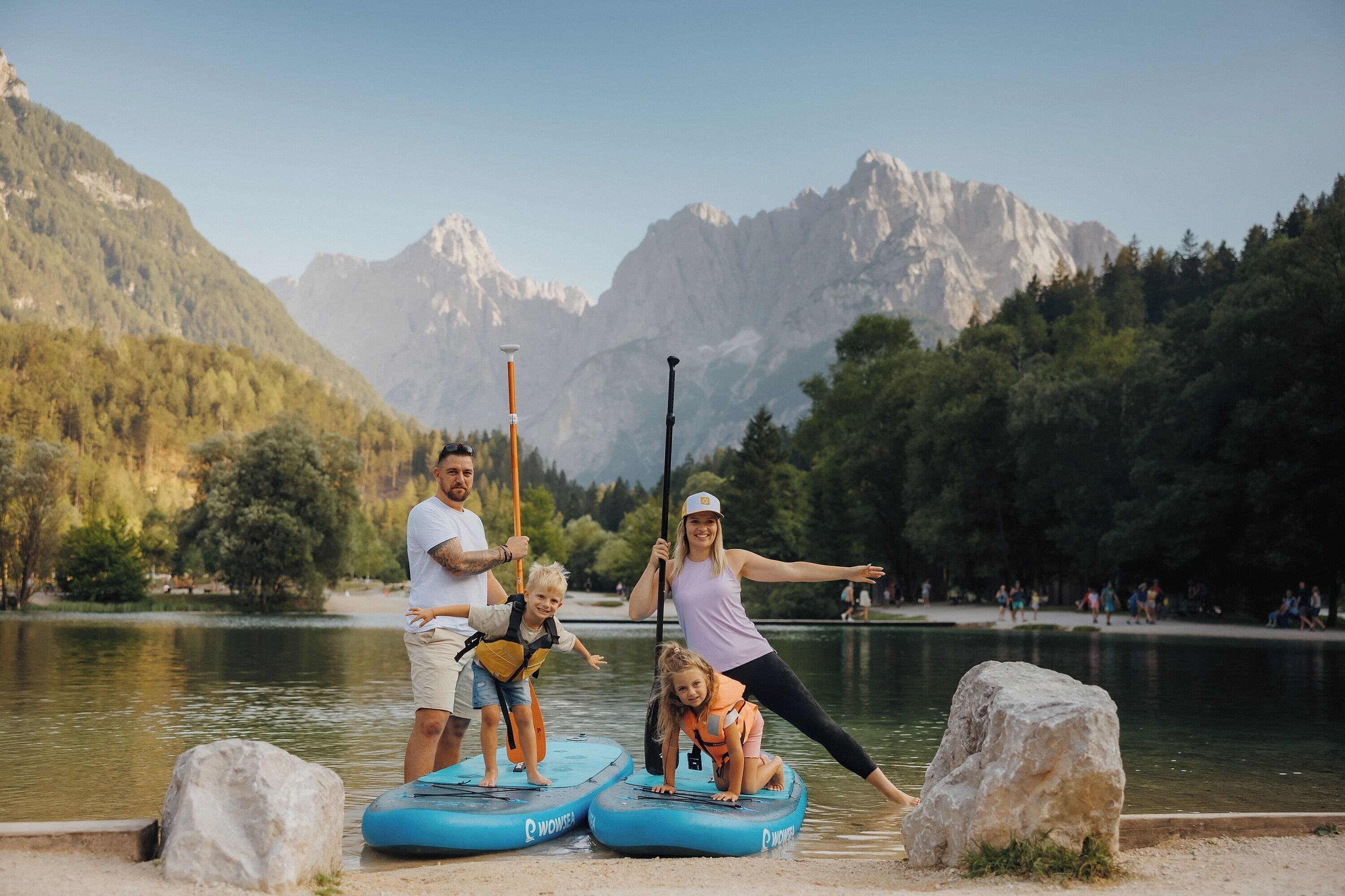 A group of people on paddleboards near a lake with mountains in the background.