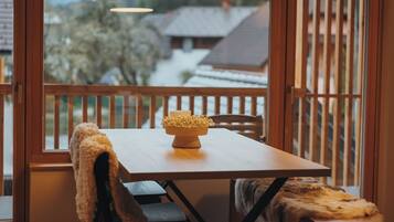 A wooden table with a bowl of flowers on a balcony overlooking a snowy landscape.