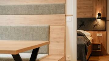 A modern bedroom with a wooden floor, a bed with a headboard, a bedside table, and a wall-mounted light fixture.