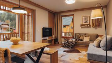 Una sala de estar acogedora con una mesa de comedor de madera, un sofá y un televisor.