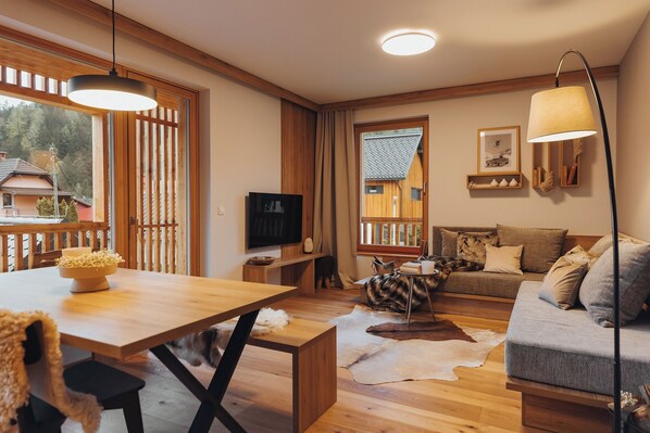 A cozy living room with a wooden dining table, a sofa, and a TV. - Goldhorn Chalet (Kranjska Gora)