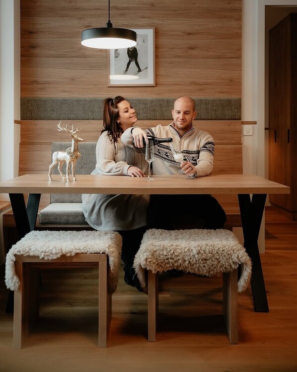 A modern dining area with a wooden table, benches, and a pendant light. - Goldhorn Chalet (Kranjska Gora)