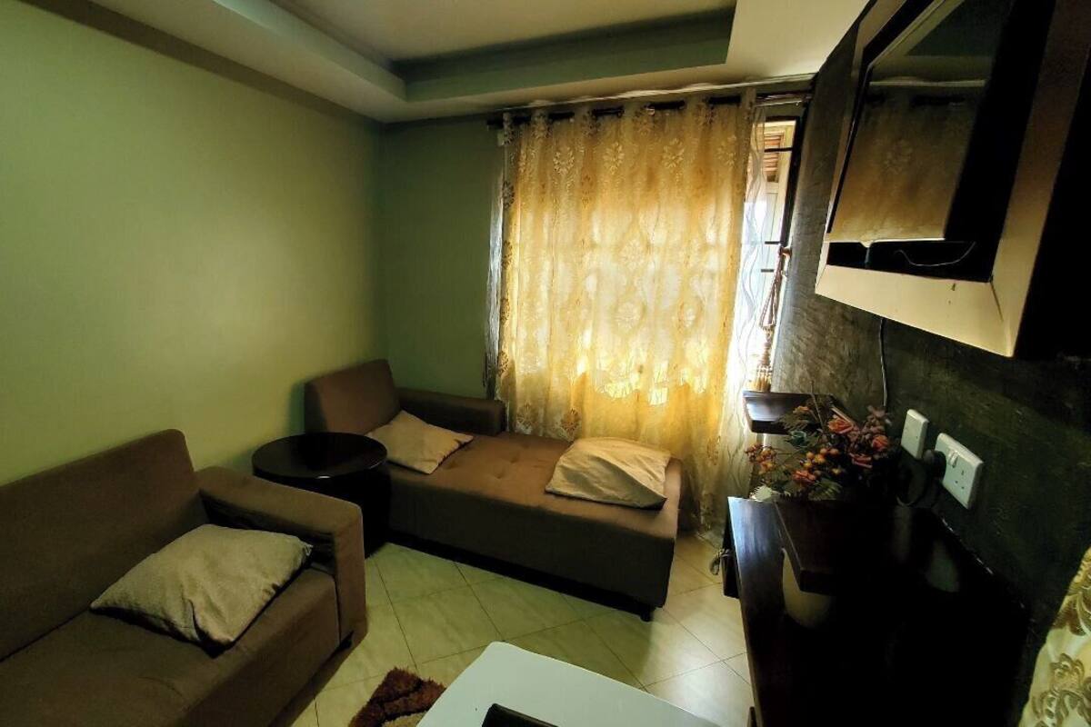 A living room with two sofas, a small table, and a TV mounted on the wall.