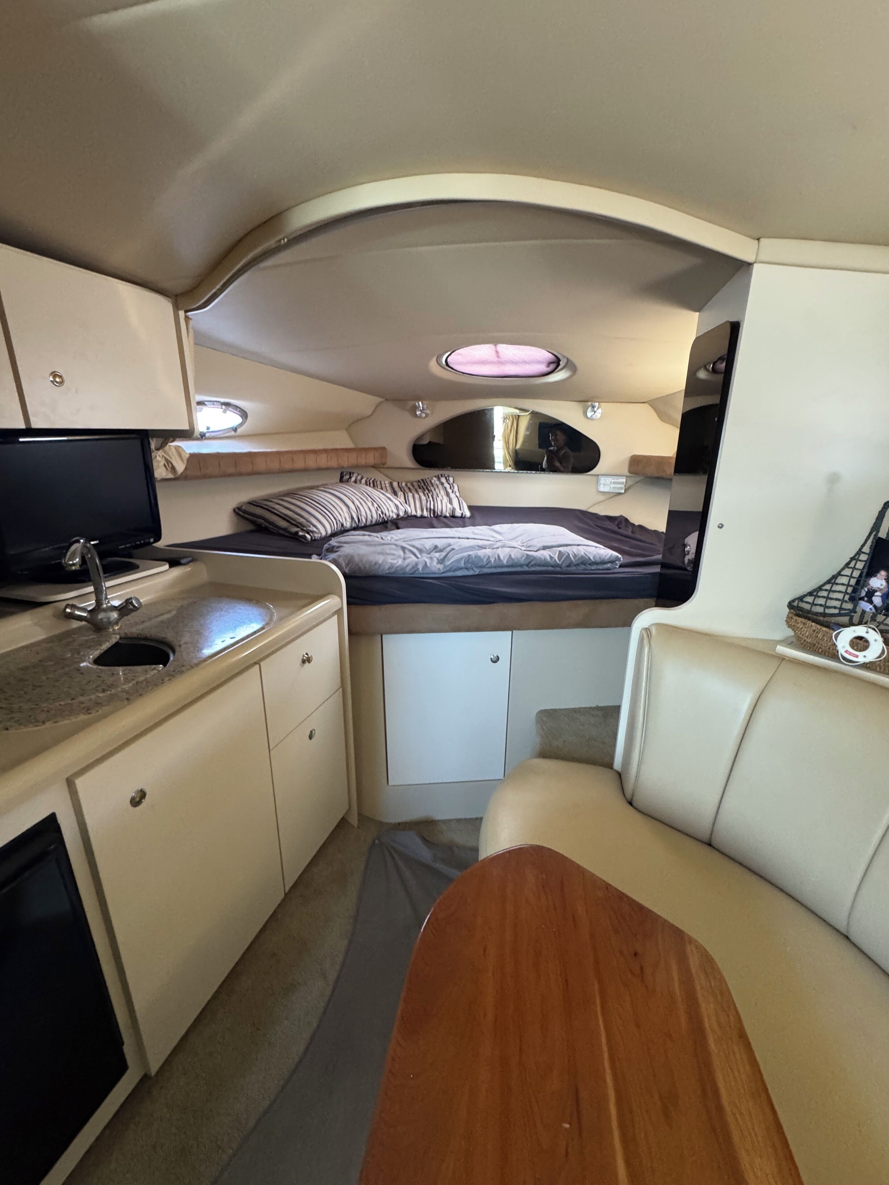 Interior de uma motorhome compacta, com cozinha compacta, cama, área de estar e um pequeno armário.