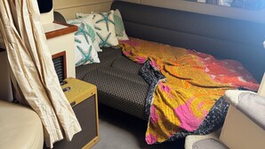 Une chambre à coucher de taille modeste, comprenant un lit, un petit canapé, une bibliothèque et un miroir.