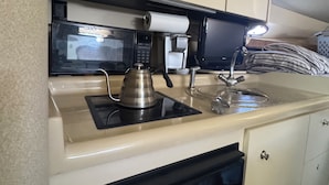 Une petite cuisine équipée d’un four à micro-ondes, d’une machine à café et d’un lave-vaisselle compact.