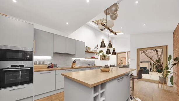 Una cucina moderna con isola centrale, forni integrati e luci a sospensione.