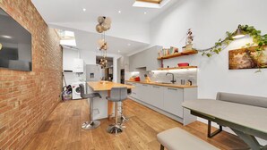 Una cucina moderna con parete in mattoni, pavimento in legno e zona pranzo con una panca.