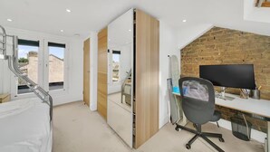 Un ufficio moderno con scrivania, sedia e monitor del computer. Una grande finestra offre vista su edifici esterni.