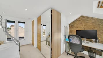 A modern office space with a desk, chair, and computer monitor. There is a large window with a view of buildings outside.