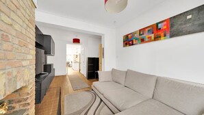 Un soggiorno moderno con un divano beige, un camino, una lampada a soffitto rossa e un quadro astratto colorato sulla parete.