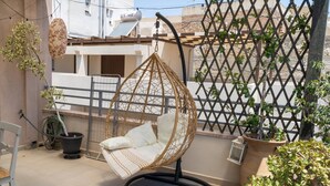 Ein Balkon mit Hängesessel, Blumentöpfen und Blick auf benachbarte Gebäude.