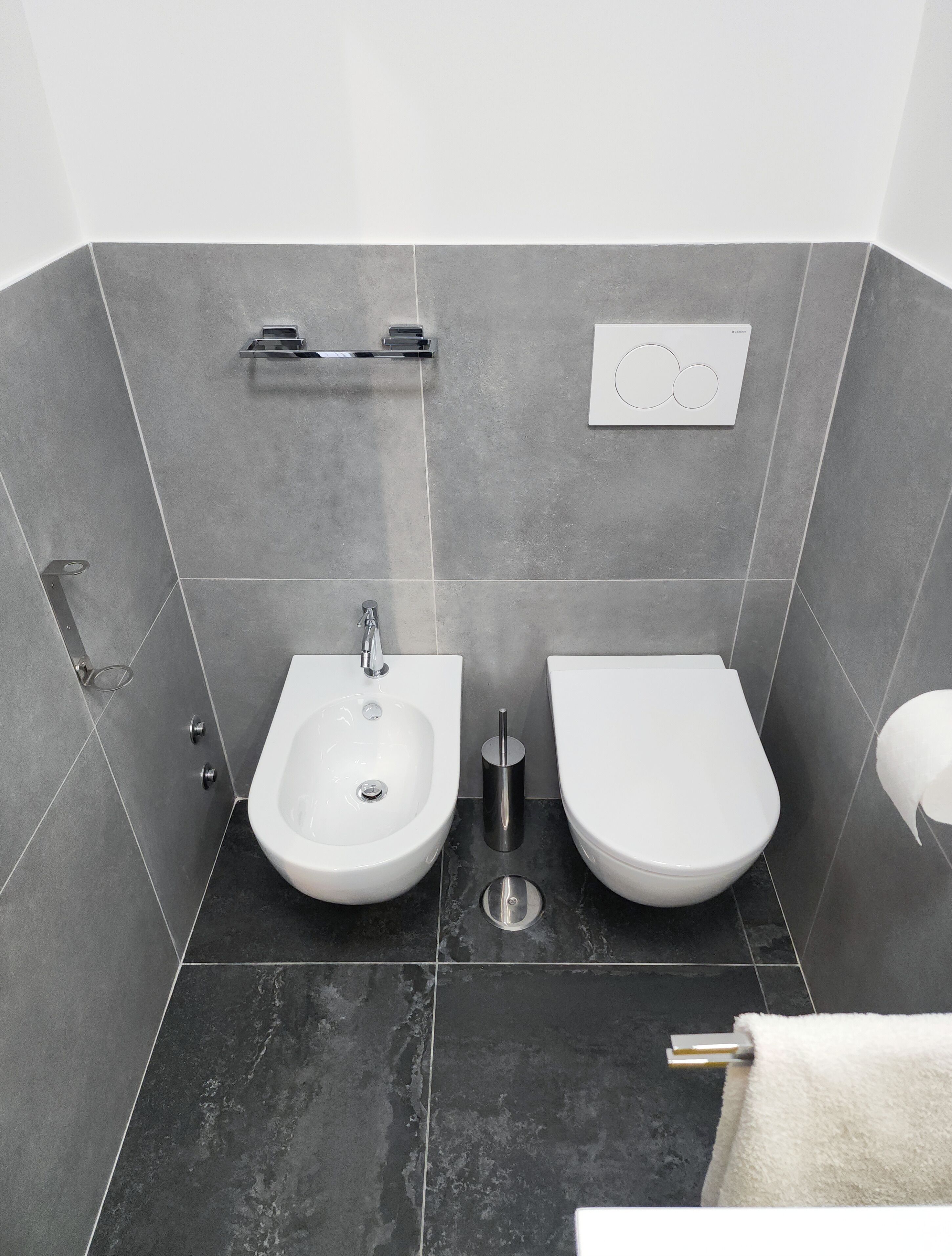 A modern bathroom with a bidet, toilet, and a towel rack.