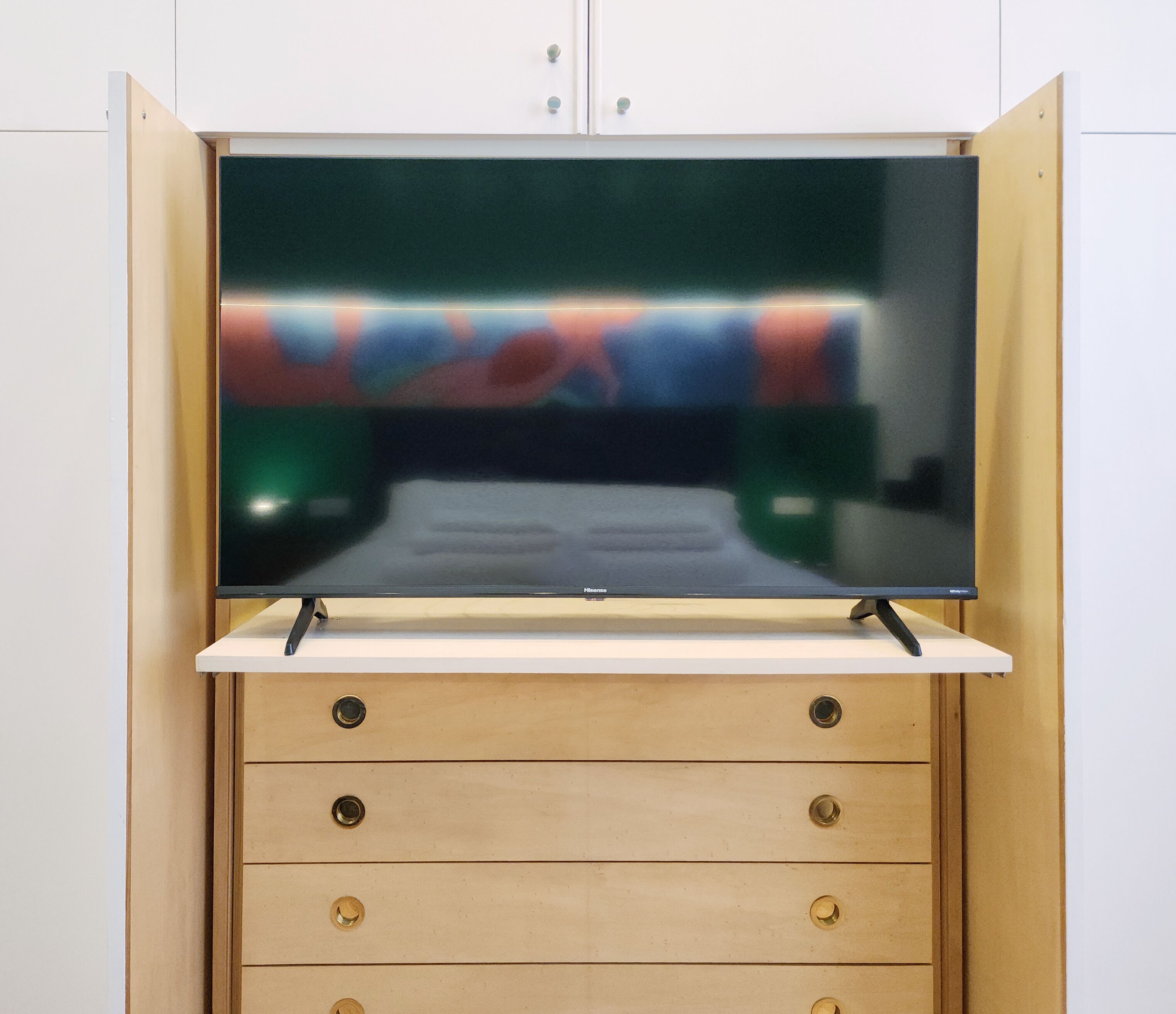 A television mounted on a wooden cabinet with a flat-screen display.