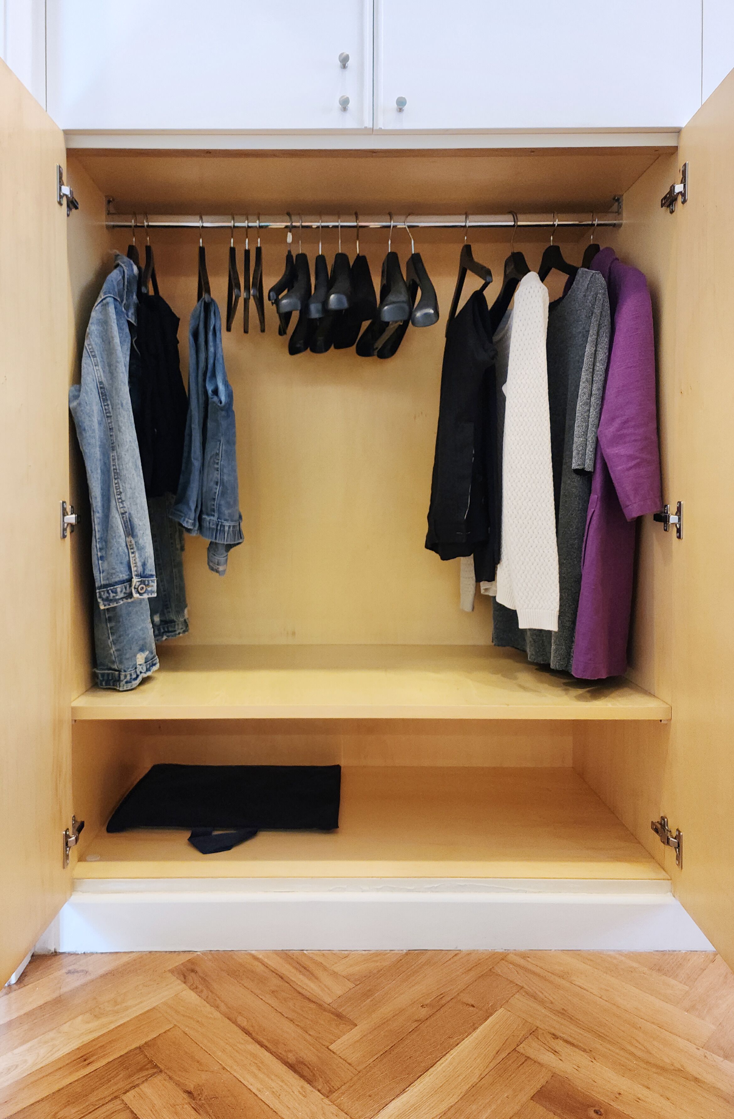 Un dressing ouvert avec des chaussures suspendues, un banc et divers vêtements.