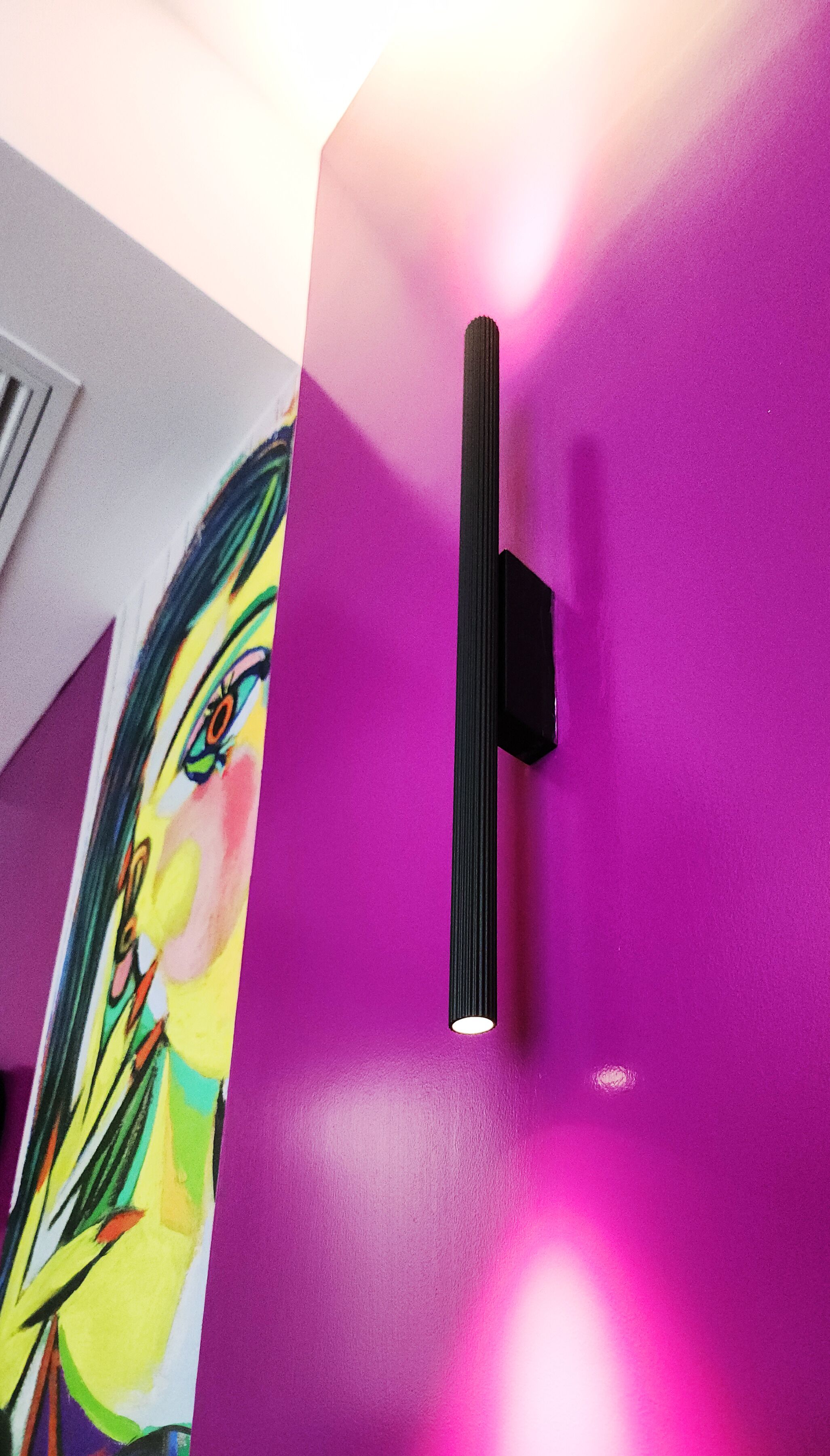 A purple wall with a black handle and a colorful painting of a face.