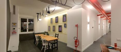 A modern interior with a dining area, a fire extinguisher, and a hallway with doors.