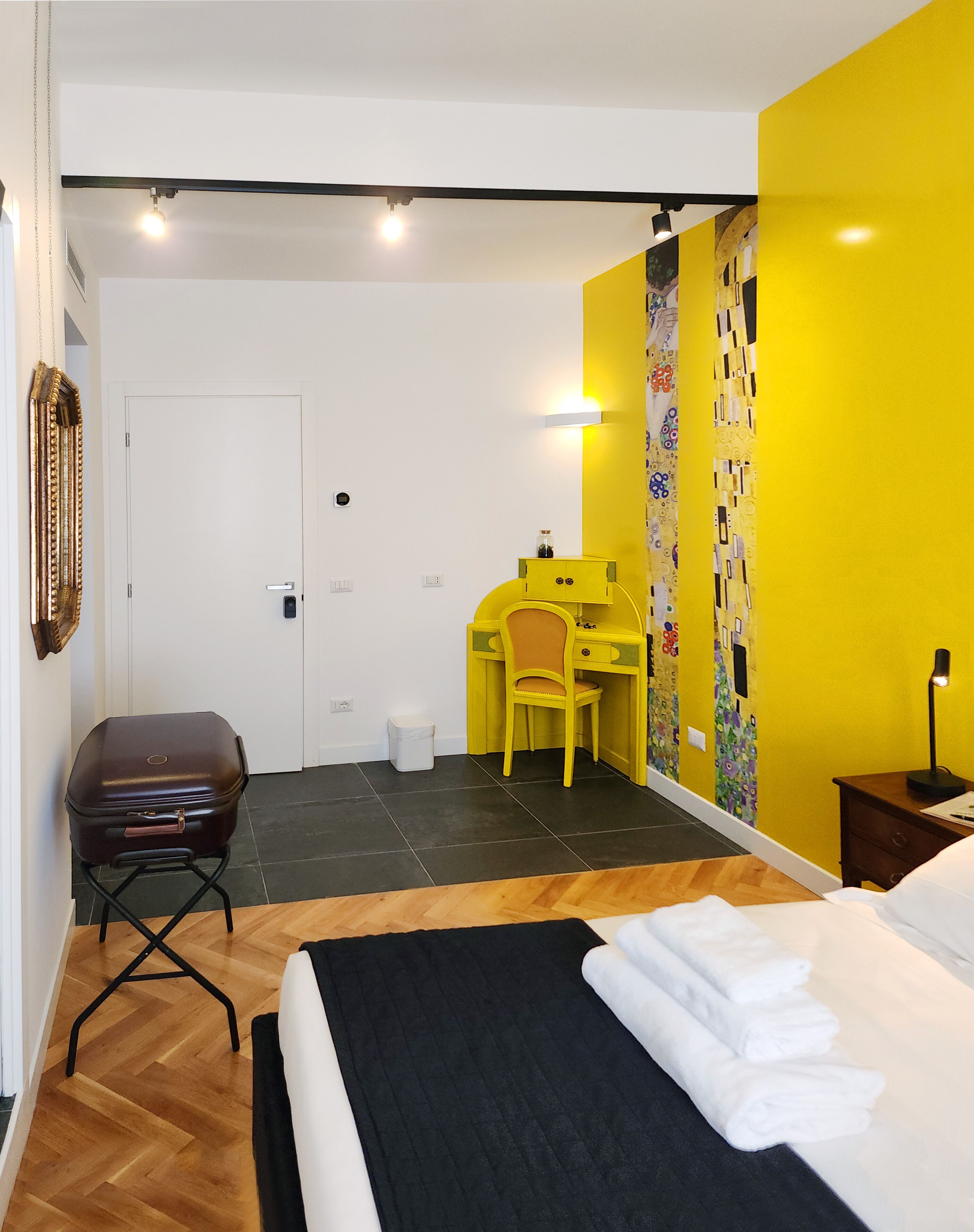 Una habitación de hotel con cama, escritorio, silla y maleta.