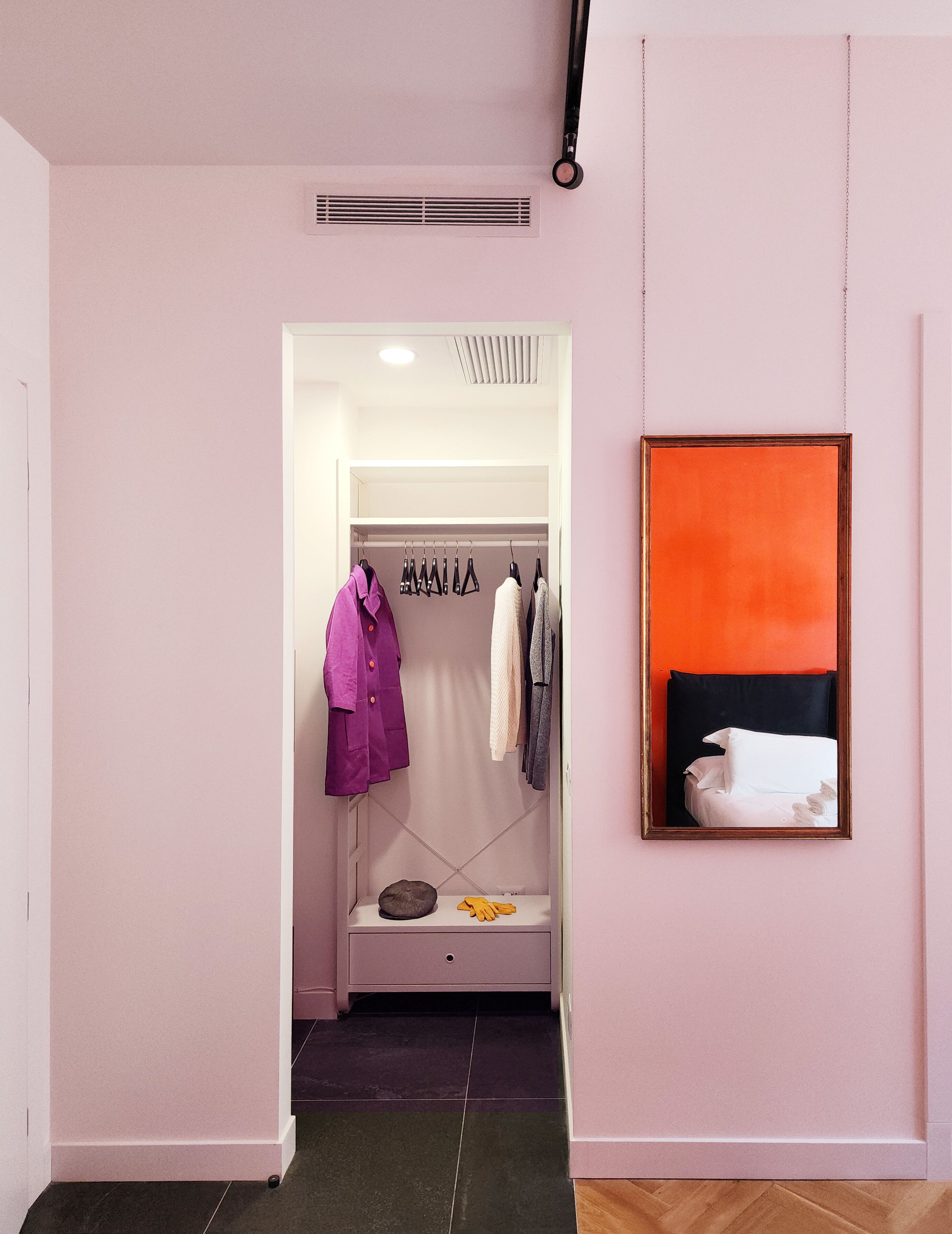 Una habitación de hotel con vestidor, cama con ropa de cama blanca y un cuadro en la pared.