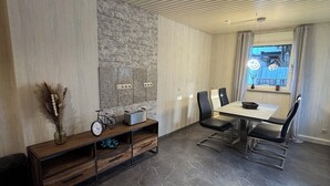 A modern dining area with a stone accent wall, a wooden console table, and a dining set.
