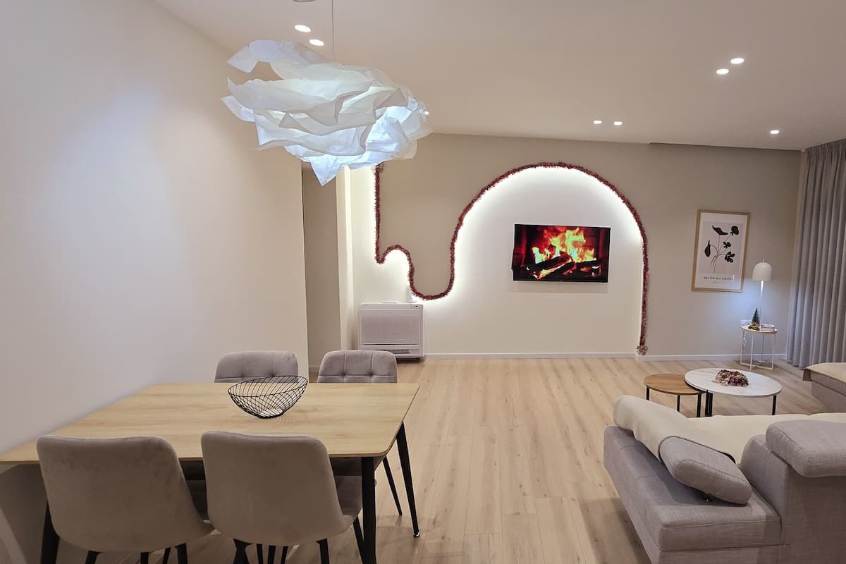 Una sala de estar moderna con una mesa de comedor de madera, sofás grises y una chimenea.