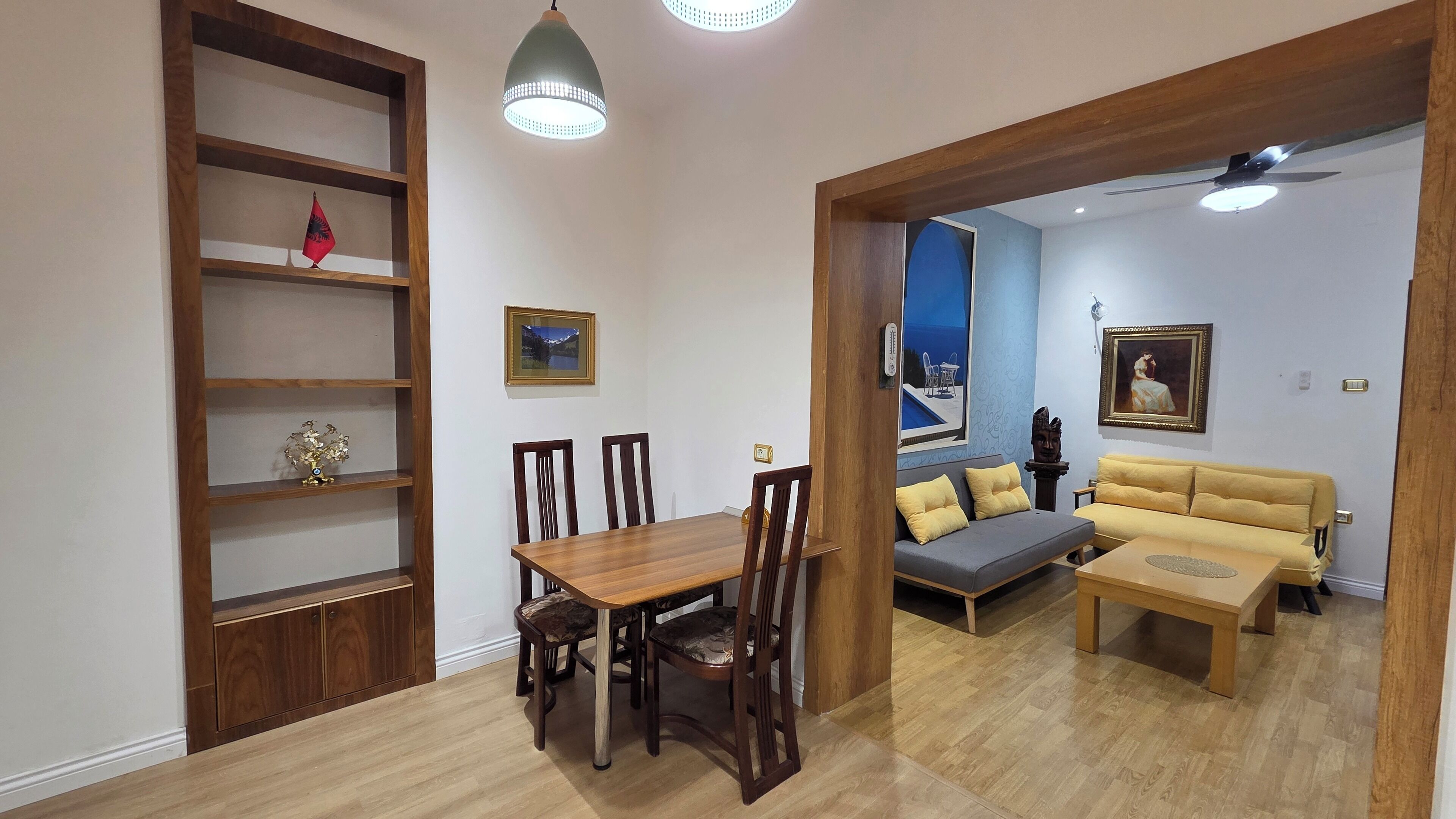 Un comedor con una mesa y sillas de madera, un sofá y una estantería.