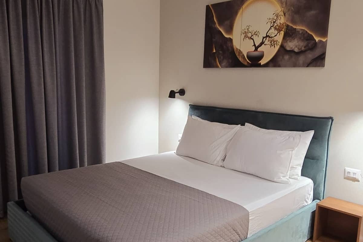 Un dormitorio moderno con cama, una lámpara de pared y un cuadro.