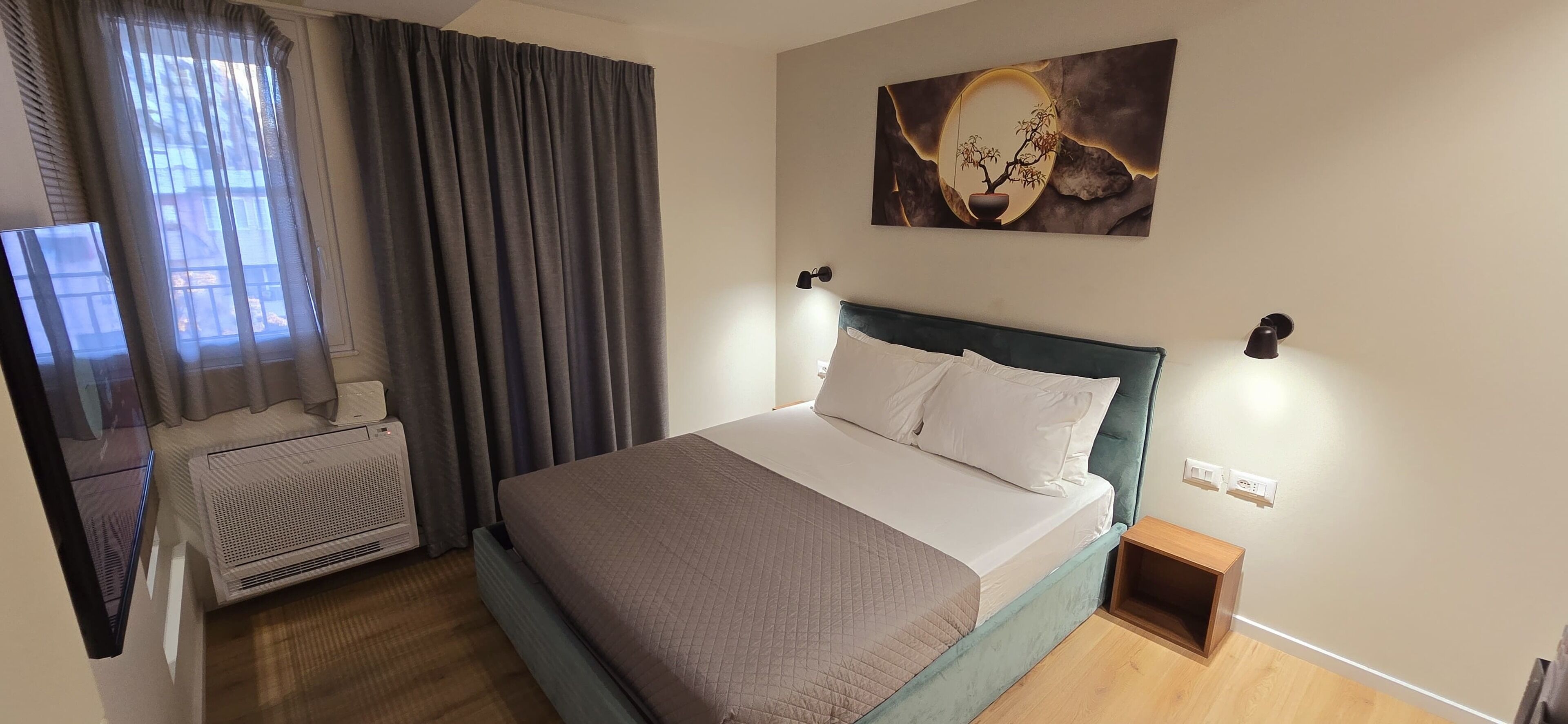 A neatly arranged bedroom with a bed, a wall-mounted artwork, and a small bedside table.