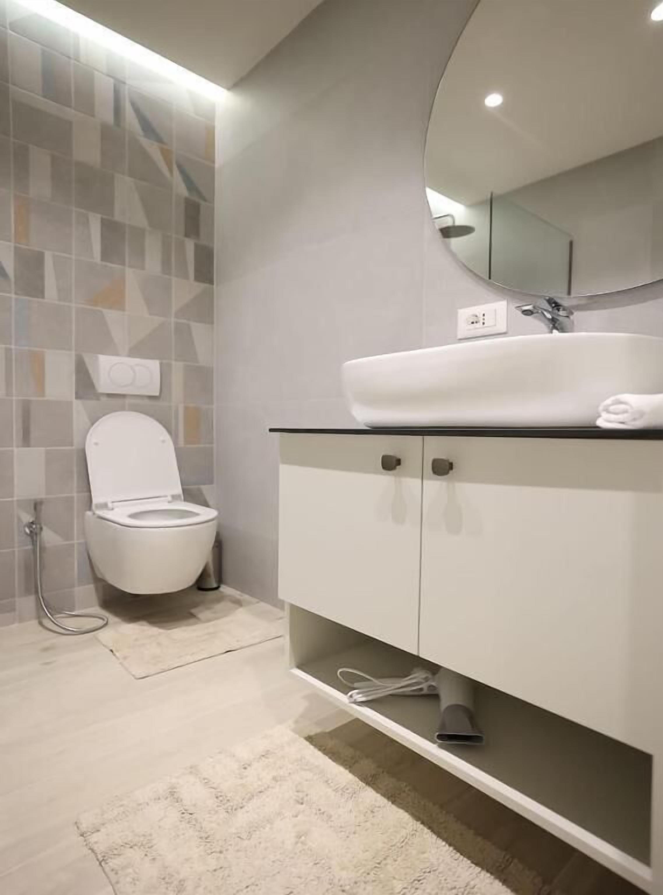 Een moderne badkamer met toilet, wastafel met spiegel en douche.