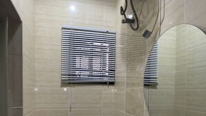Une salle de bain avec des toilettes, un lavabo et une fenêtre équipée de stores.