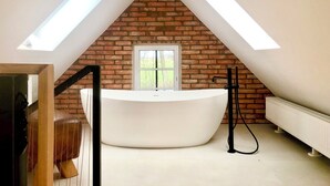 A modern bathroom with a freestanding bathtub, skylights, and a brick wall. - Special design apartment in the countryside for your time out in the north (Wangerland)