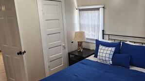 A bedroom with a bed, a nightstand, a lamp, and a window with curtains.