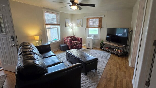 A living room with a leather sofa, a coffee table, a TV, and a ceiling fan.