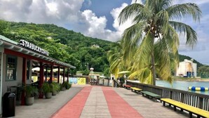 A wooden boardwalk leading to a Starbucks coffee shop with a red carpet, palm trees, and a view of a body of water. - Beach and Bliss E32 - Ocho Rios Retreats (Ocho Rios)