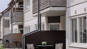 A multi-story residential building with balconies, a small outdoor seating area with a table and chairs, and a pathway leading to the entrance. - GotlandStay Volontären (Visby)