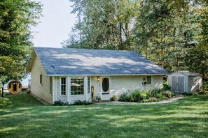 A single-story house with a gabled roof, a front porch, and a small attached shed.