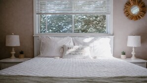 Una cama cuidadosamente tendida con ropa blanca y una almohada que dice 'Wanderlust: un fuerte deseo de vagar y explorar el mundo'.