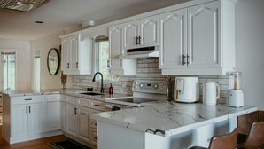 Una cocina moderna con armarios blancos, una isla central y un horno empotrado.