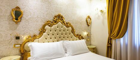 A luxurious bedroom with a tufted headboard, a classic mirror, and a bedside table with a lamp.