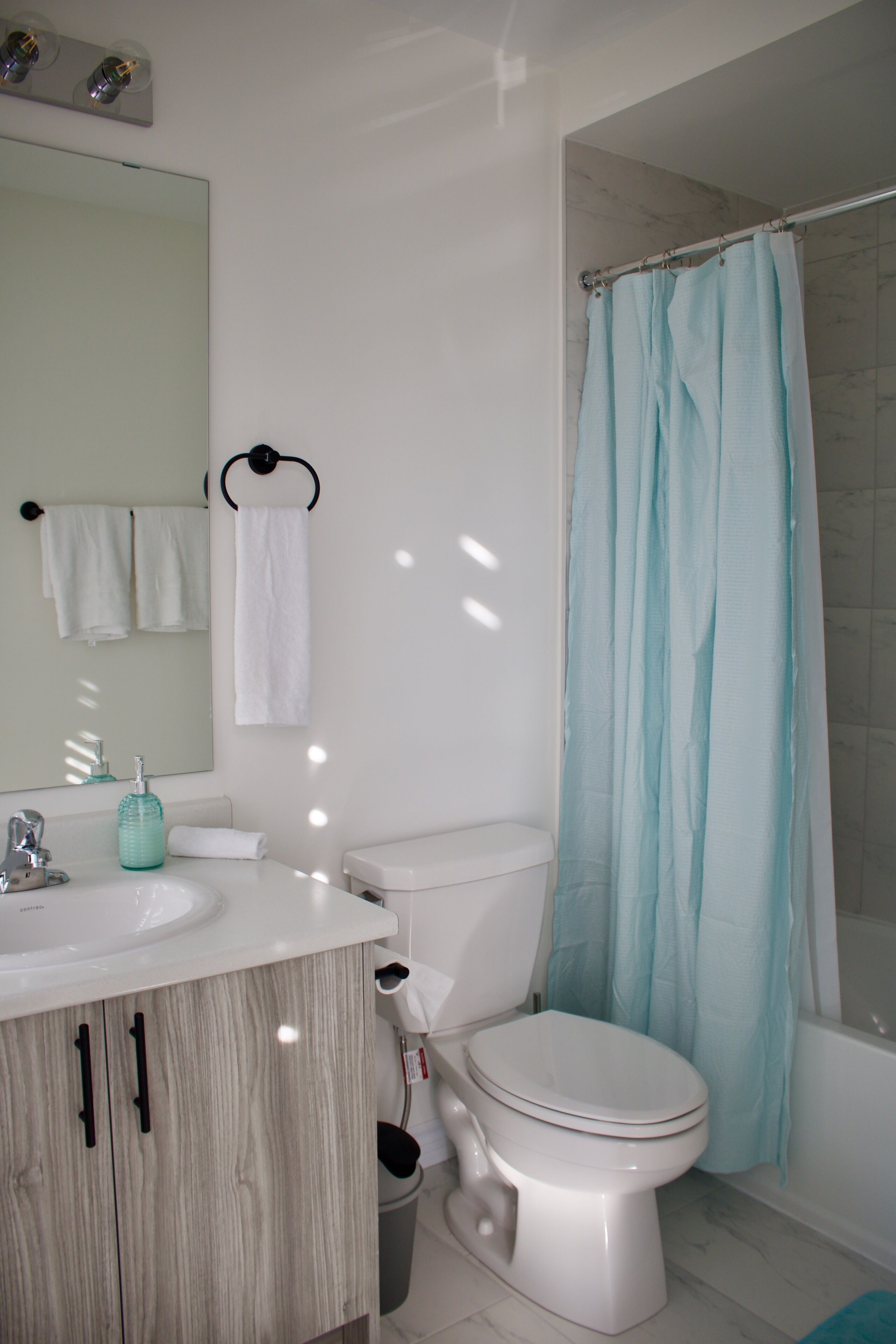 A bathroom with a white sink, a toilet, a mirror, and a shower curtain.