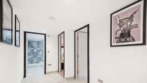 A hallway with a marble floor, framed pictures on the walls, and a Dior advertisement.