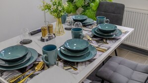 A dining table set with teal plates, matching cups, and gold cutlery. - Premium Serviced Accommodation Nottingham - 4 Bedrooms - All Ensuite - Sleeps 7 (Nottingham)