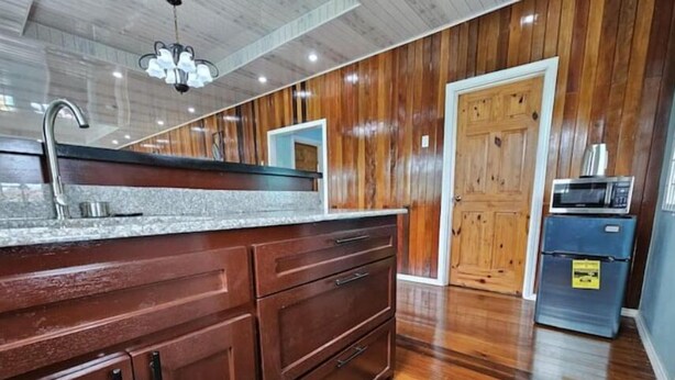 A kitchen with wooden cabinets, a granite countertop, a stainless steel sink, and a microwave. - DougVille 43
 Tranquillity and Peace await! (Venezuela Scheme)