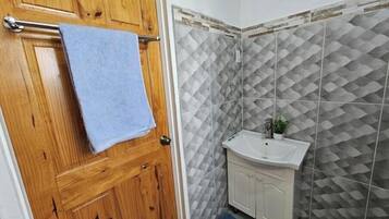 A bathroom with a wooden door, a sink, and patterned tiles.