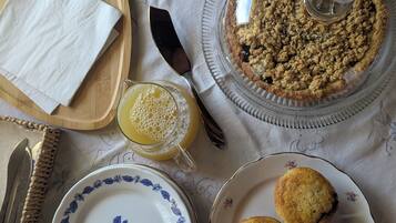 Une table avec une tarte, des muffins, un pichet de jus de fruits et une assiette décorée de motifs floraux.