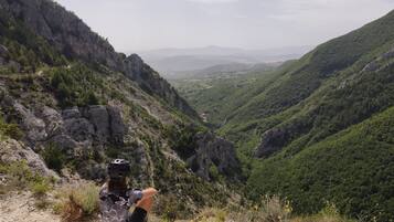 Uma pessoa sentada em afloramento rochoso com vista para um vale com penhascos íngremes e vegetação densa.